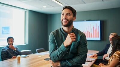 Homem em uma sala de reunião com a equipe e um gráfico de crescimento